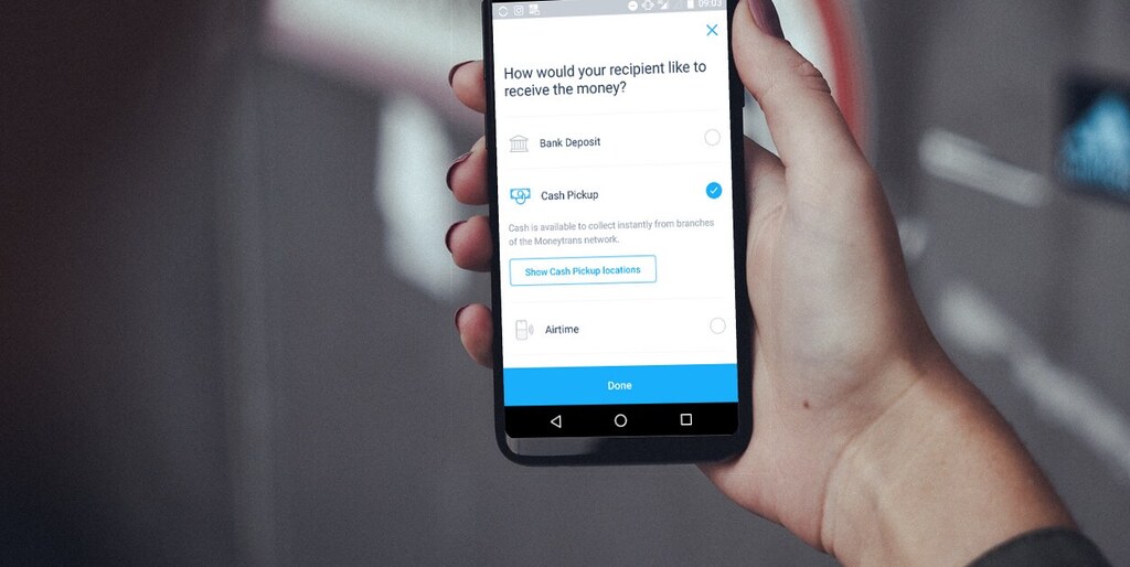 Hand holding a smartphone showing a money transfer application screen